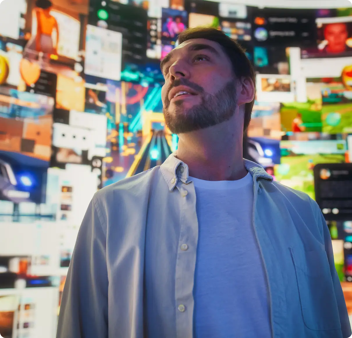 Man surrounded by colorful digital screens.